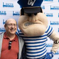 An alum poses with Louie the Laker